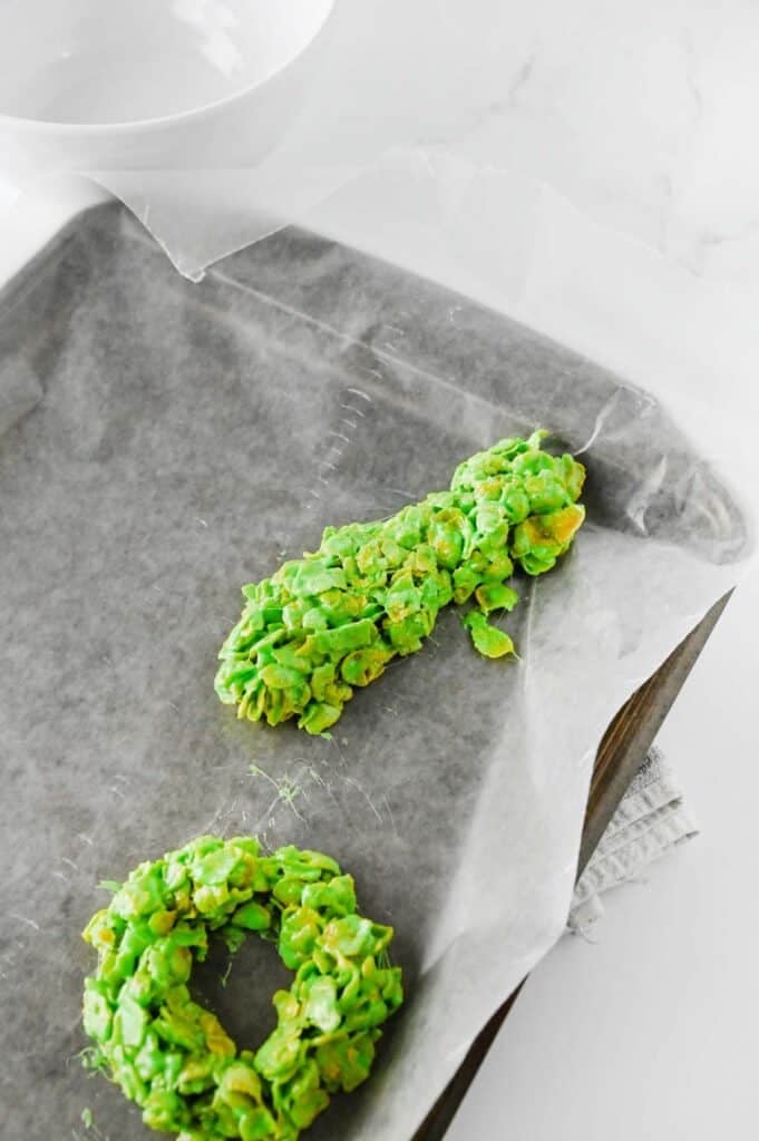 green cornflake mixture being formed on parchment lined baking sheet