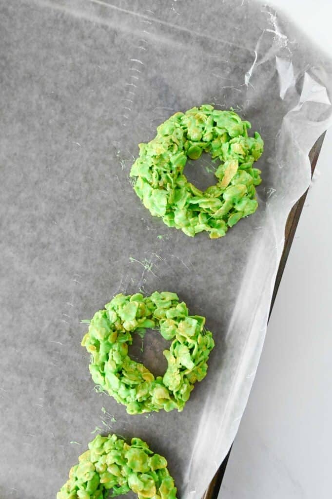 green cornflake mixture shaped into rings on a parchment lined baking sheet