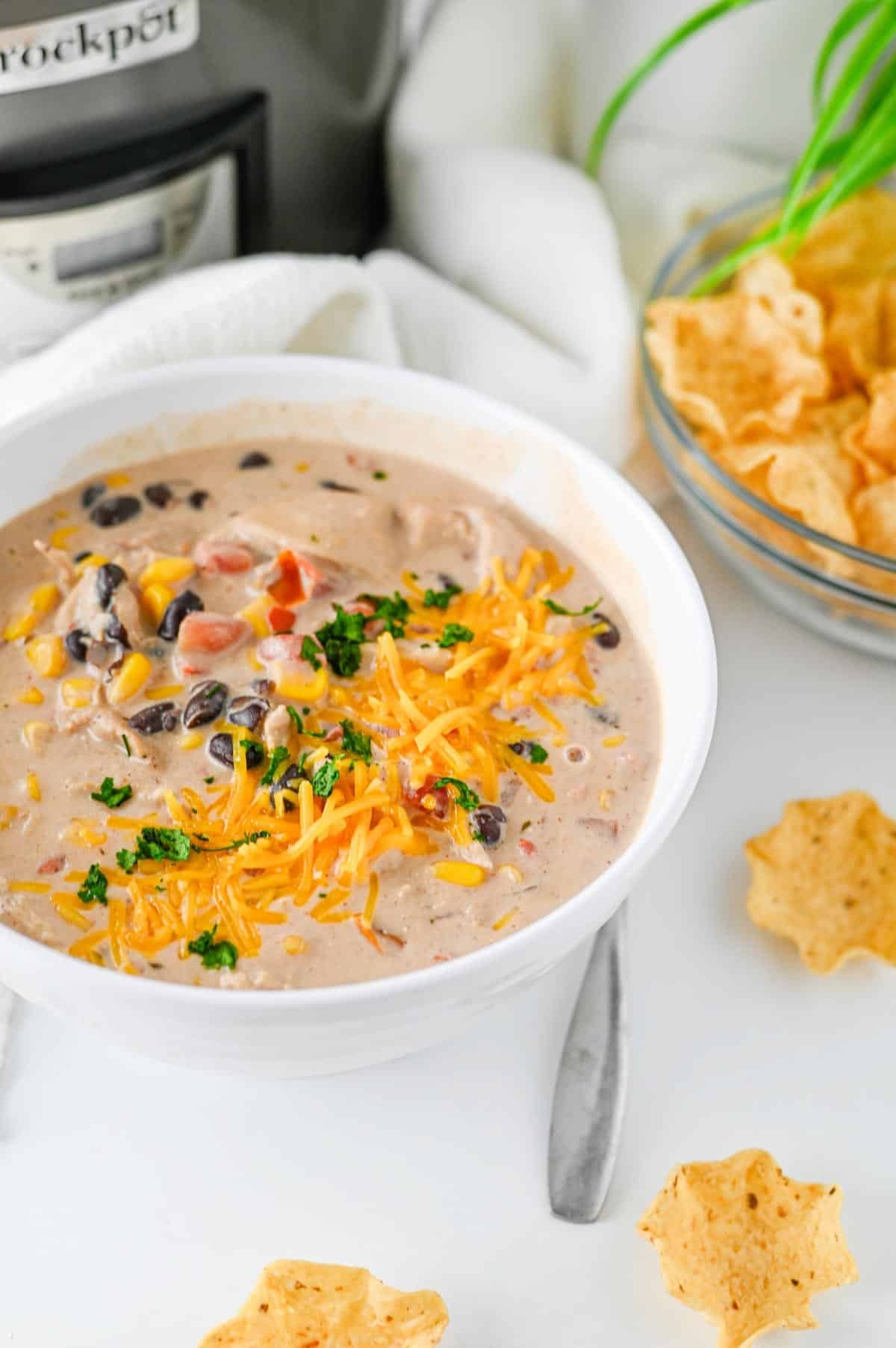 bowl of cream cheese chicken chili surrounded by tostitos scoops