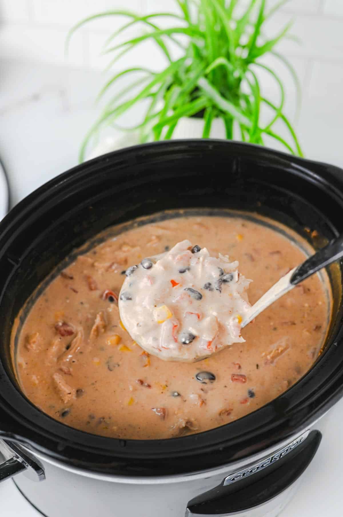 full ladle of cream cheese chicken chili over a crock pot