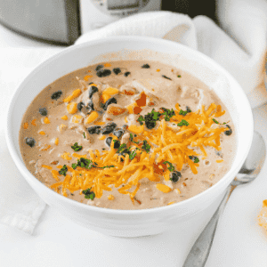 This Cream Cheese Chicken Chili is an easy crock pot dinner made with tender shredded chicken, black beans, corn, diced tomatoes, ranch seasoning, chicken broth, warm spices and cream cheese for the perfect creamy finish. This slow cooker chicken chili is rich, hearty and packed with flavor, making it a cozy weeknight dinner, game day meal or simple family comfort food recipe. Serve this creamy chicken chili with shredded cheese, cilantro, tortilla chips or over rice for a filling bowl everyone will love. If you need easy slow cooker recipes, crock pot chicken recipes, creamy chili recipes or simple dinner ideas with chicken thighs or chicken breasts, this Cream Cheese Chicken Chili is a must try.