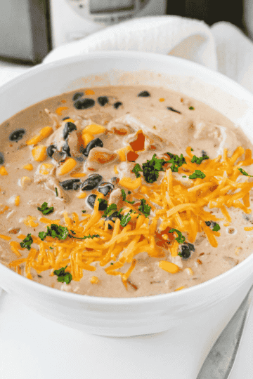 This Cream Cheese Chicken Chili is an easy crock pot dinner made with tender shredded chicken, black beans, corn, diced tomatoes, ranch seasoning, chicken broth, warm spices and cream cheese for the perfect creamy finish. This slow cooker chicken chili is rich, hearty and packed with flavor, making it a cozy weeknight dinner, game day meal or simple family comfort food recipe. Serve this creamy chicken chili with shredded cheese, cilantro, tortilla chips or over rice for a filling bowl everyone will love. If you need easy slow cooker recipes, crock pot chicken recipes, creamy chili recipes or simple dinner ideas with chicken thighs or chicken breasts, this Cream Cheese Chicken Chili is a must try.