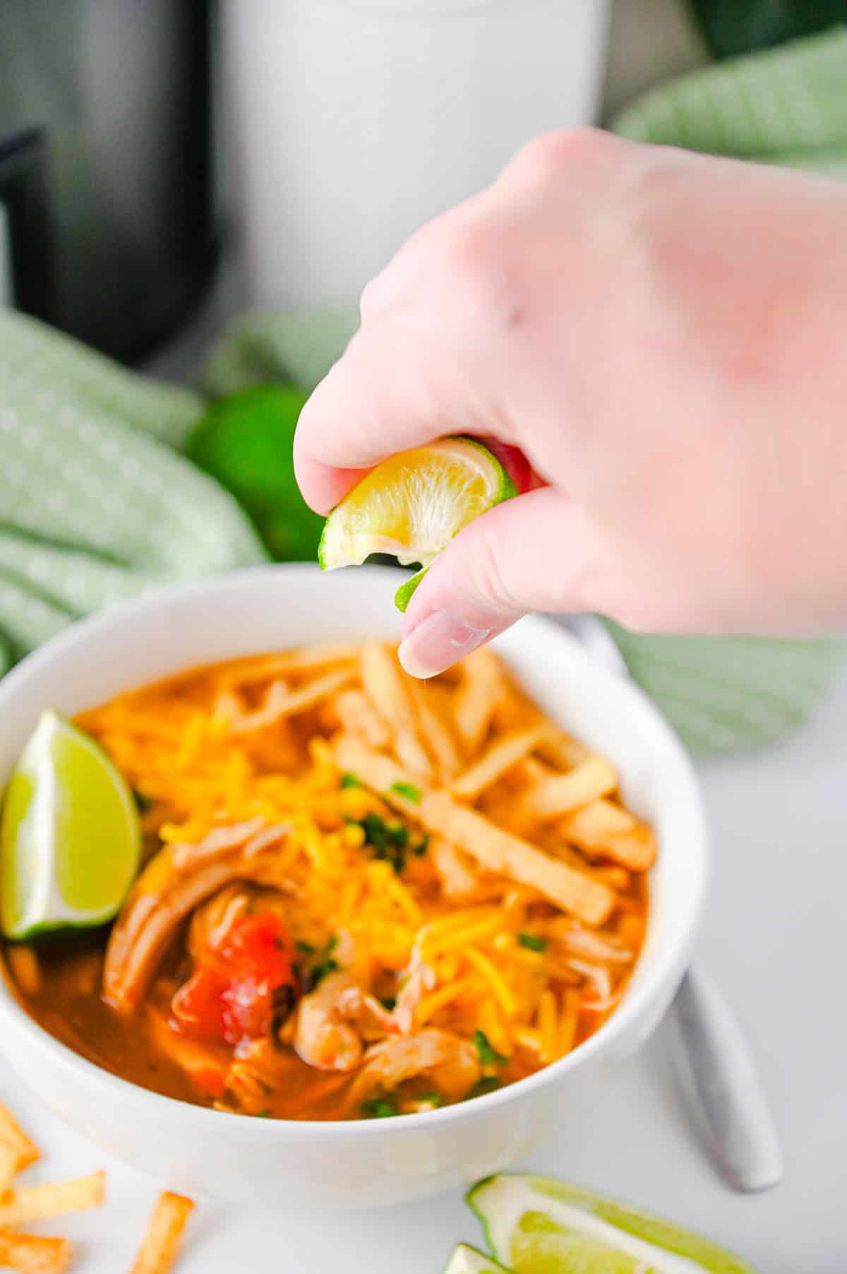 lime wedge being squeezed over bowl of chicken enchilada soup