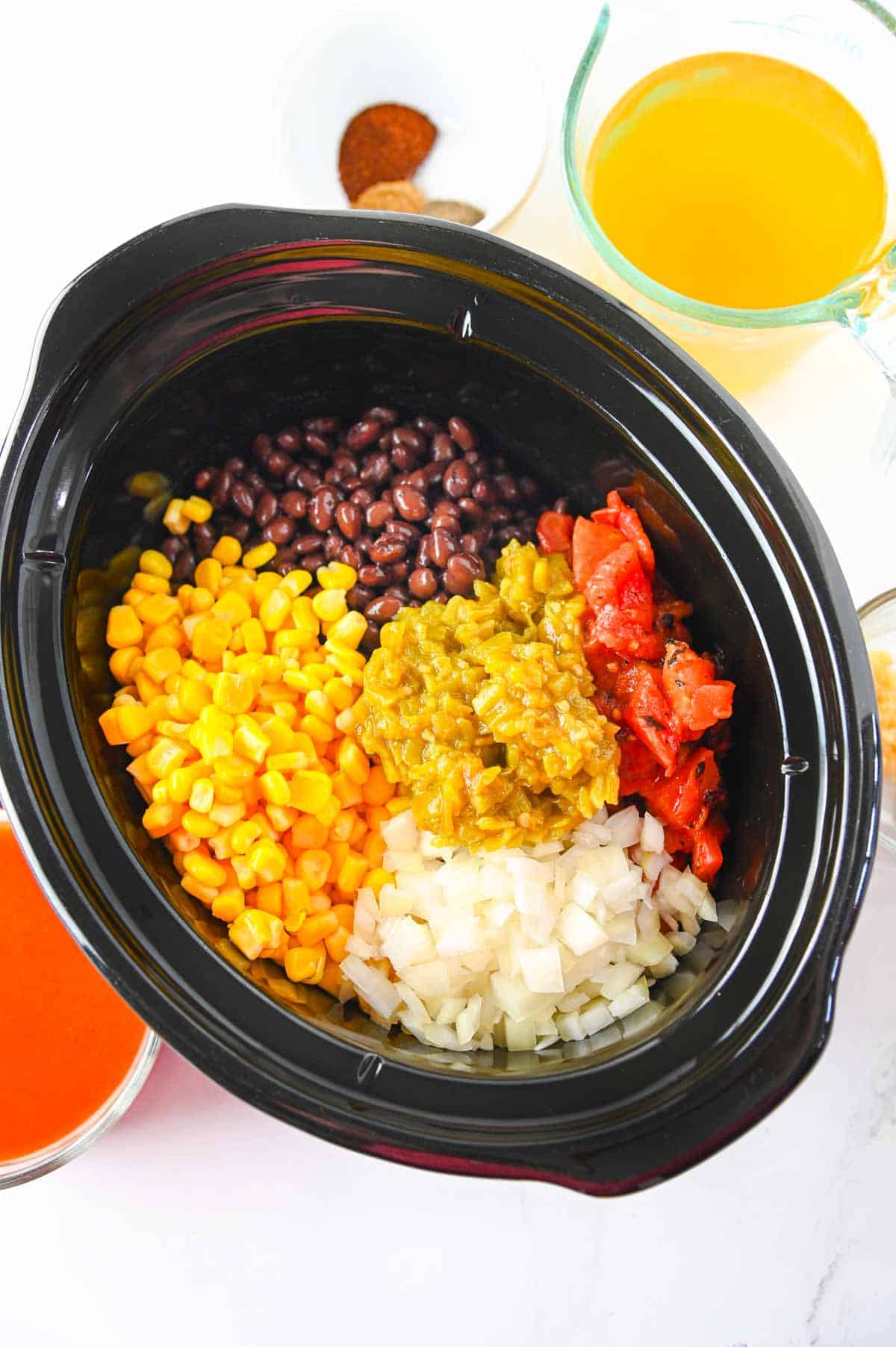corn, green chilies, tomatoes and beans in a crock pot