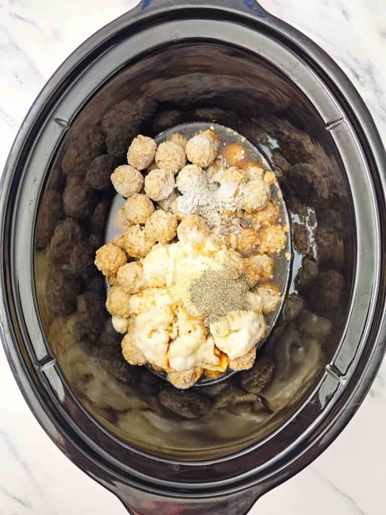 condensed soup and seasonings added to slow cooker with meatballs