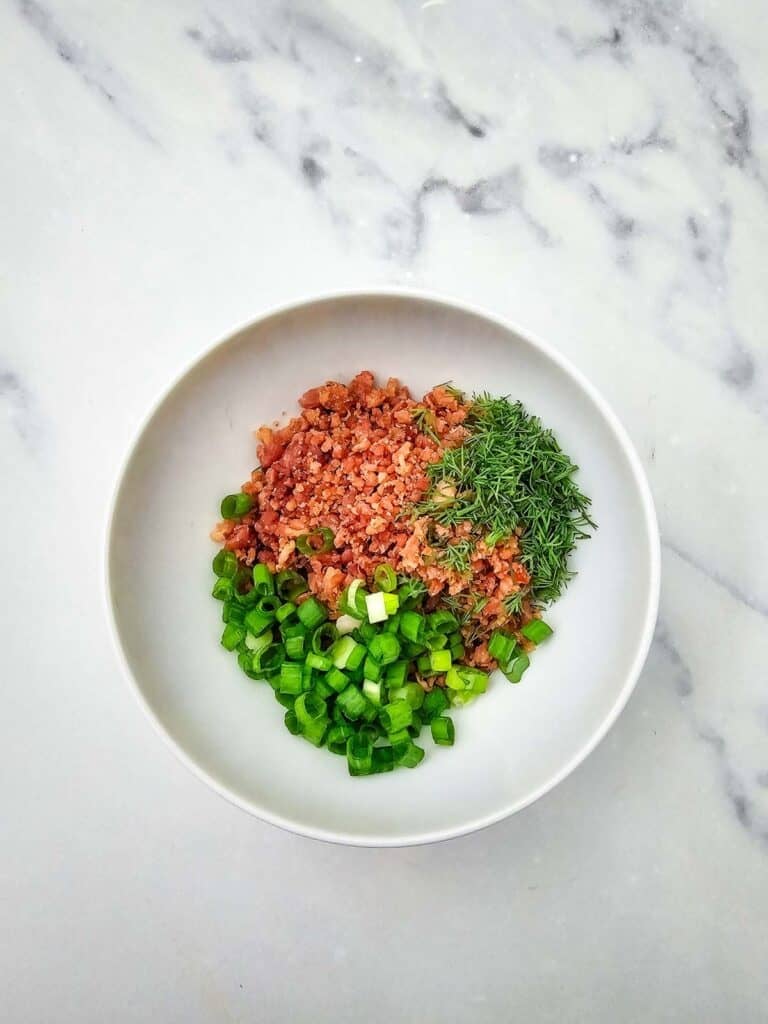 crumbled bacon, chopped dill and chopped green onions on a plate