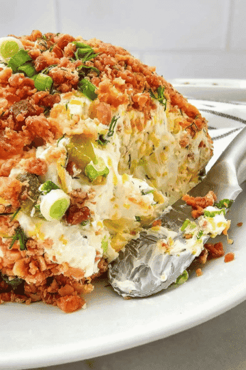 This Dill Pickle Cheese Ball is the ultimate easy party appetizer for pickle lovers! Made with cream cheese, shredded cheddar, chopped dill pickles, pickle juice, green onions and fresh dill, this creamy cheese ball recipe is packed with tangy, savory flavor. Rolled in crispy bacon pieces, green onions and dill, it's a delicious no bake appetizer that's perfect for holiday parties, Christmas gatherings, Thanksgiving appetizers, game day snacks and potlucks. Serve this bacon dill pickle cheese ball with crackers, pretzels or fresh veggies for an easy make ahead appetizer everyone will want to try. If you're looking for cream cheese appetizers, pickle recipes, easy cheese ball recipes or crowd pleasing party dips, save this dill pickle appetizer recipe!