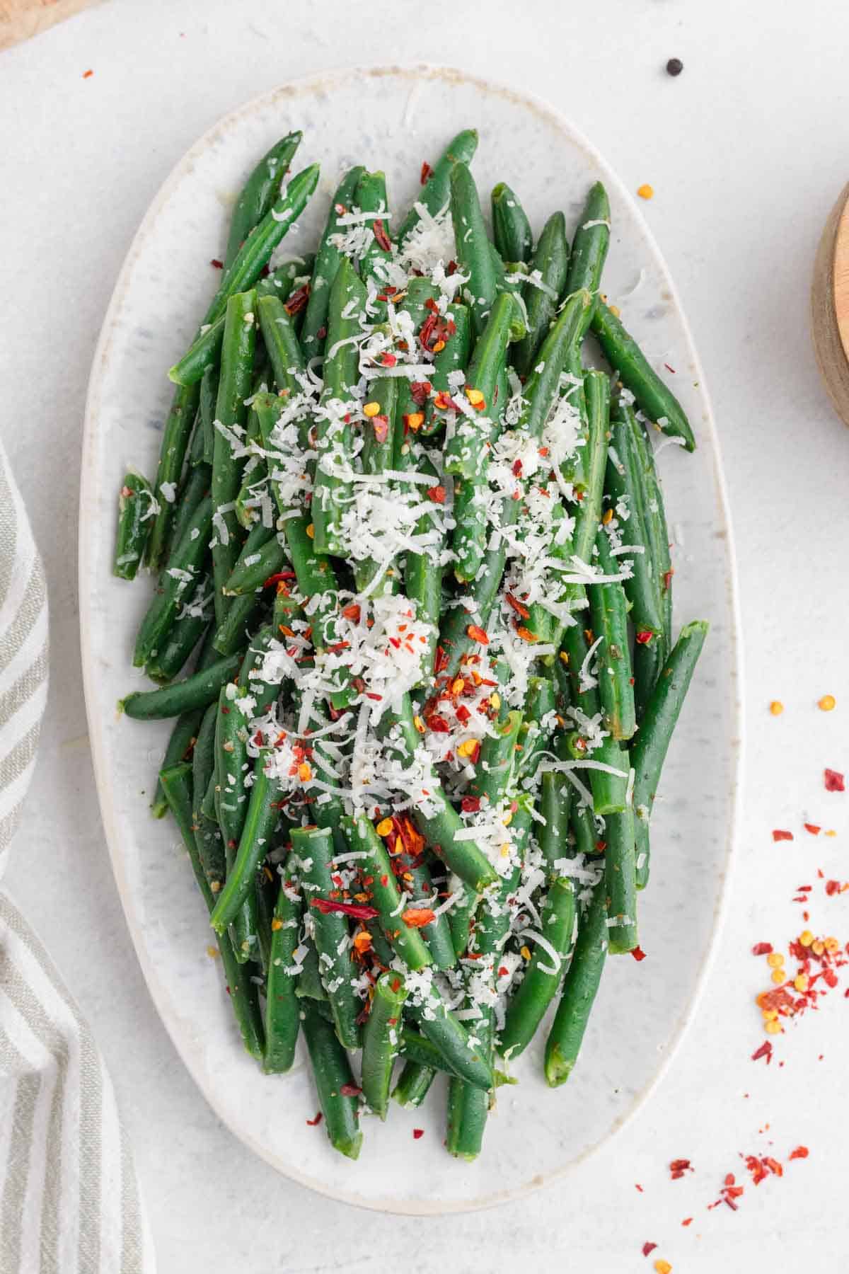 shredded parmesan on top of green beans on a plate