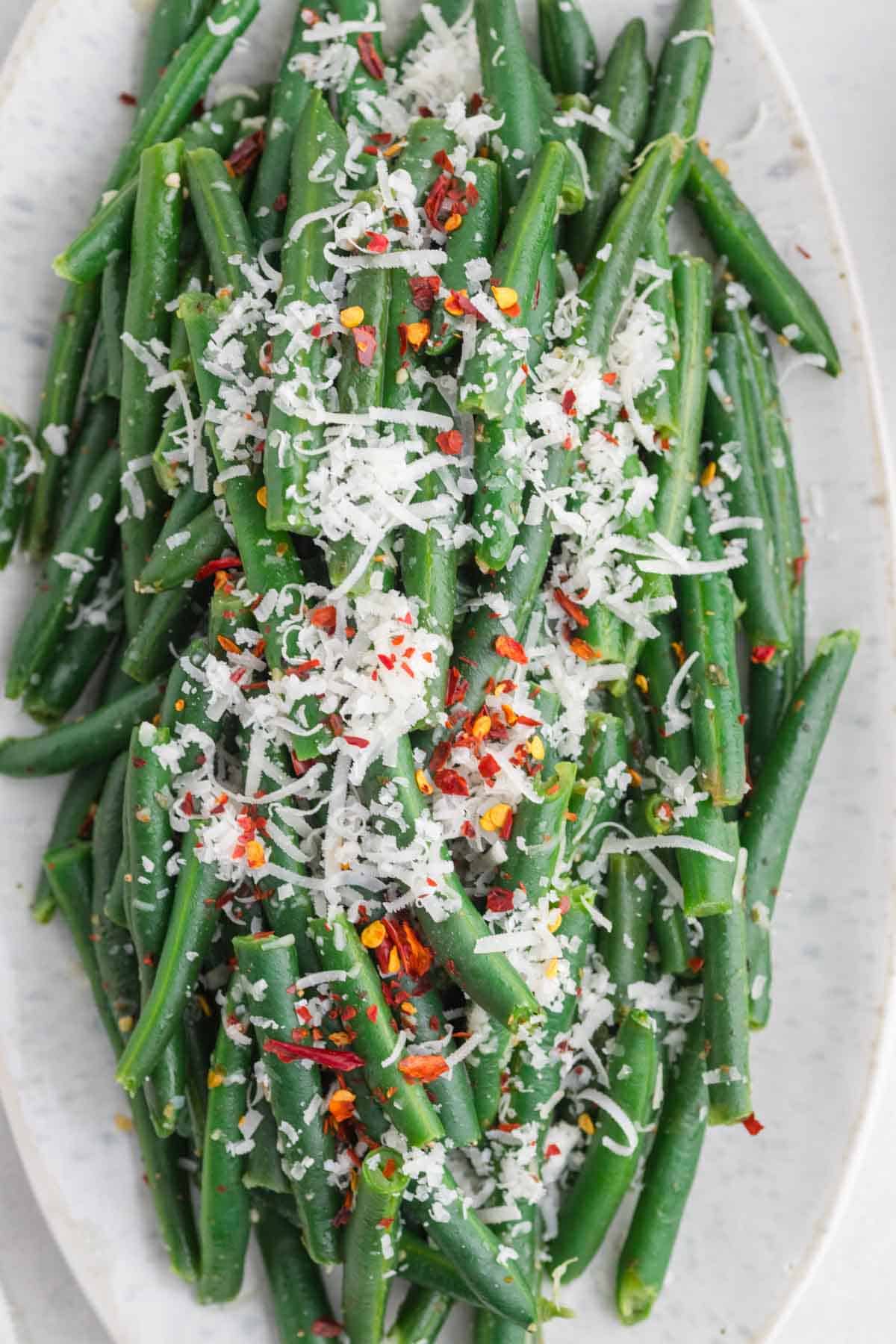 shredded parmesan and chili flakes on top of green beans