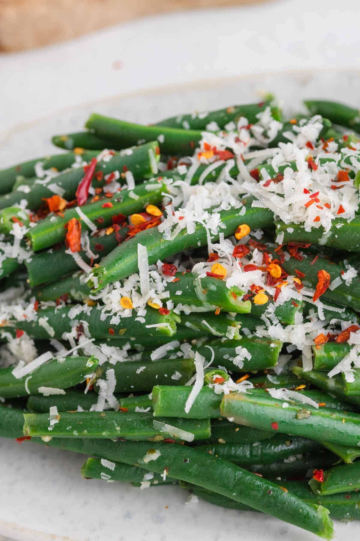 chili flakes and shredded cheese on top of green beans