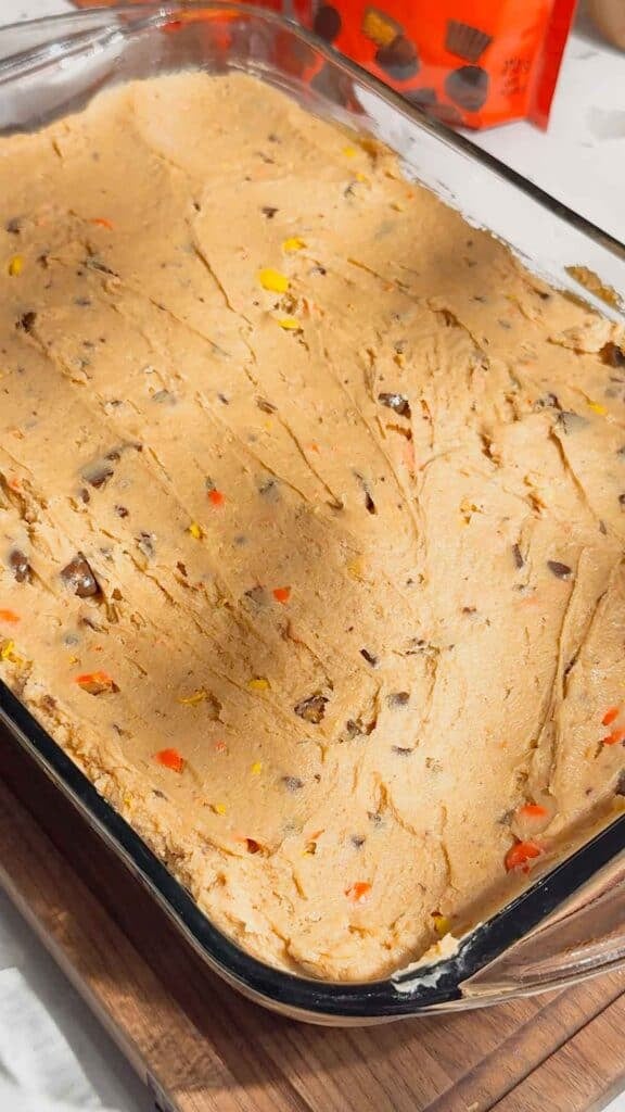 peanut butter cheesecake mixture spread over oreo crust in a 9 x 13 inch baking dish