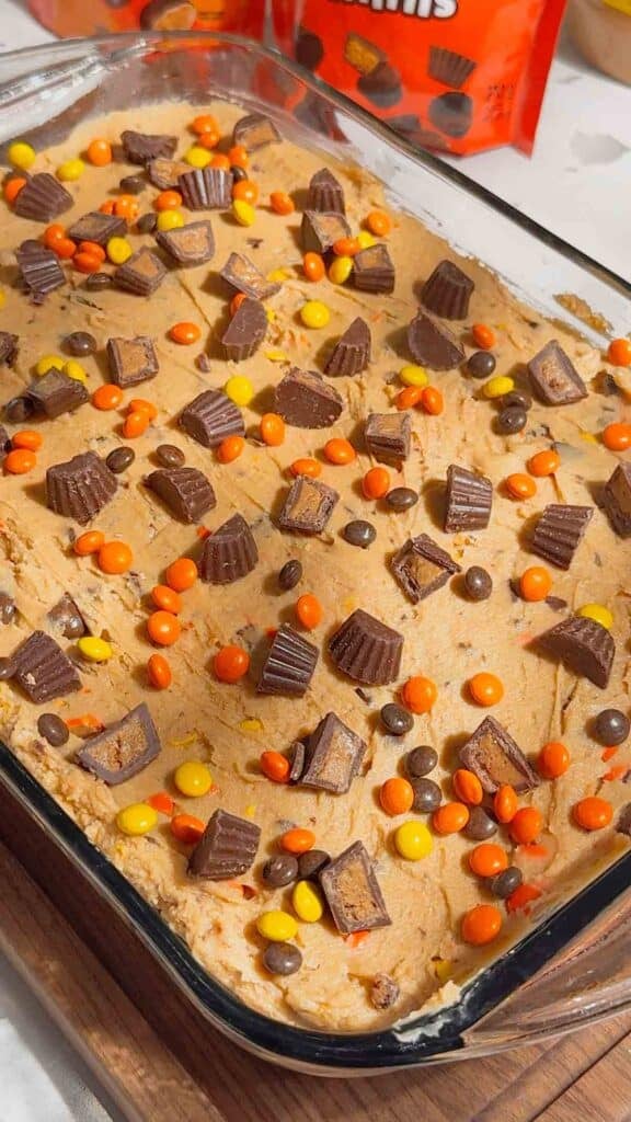mini reese's and chopped peanut butter cups on top of a peanut butter cheesecake