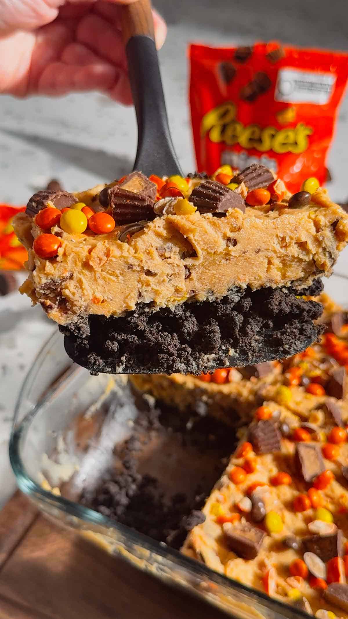 lifting a slice of loaded reese's cheesecake from the pan