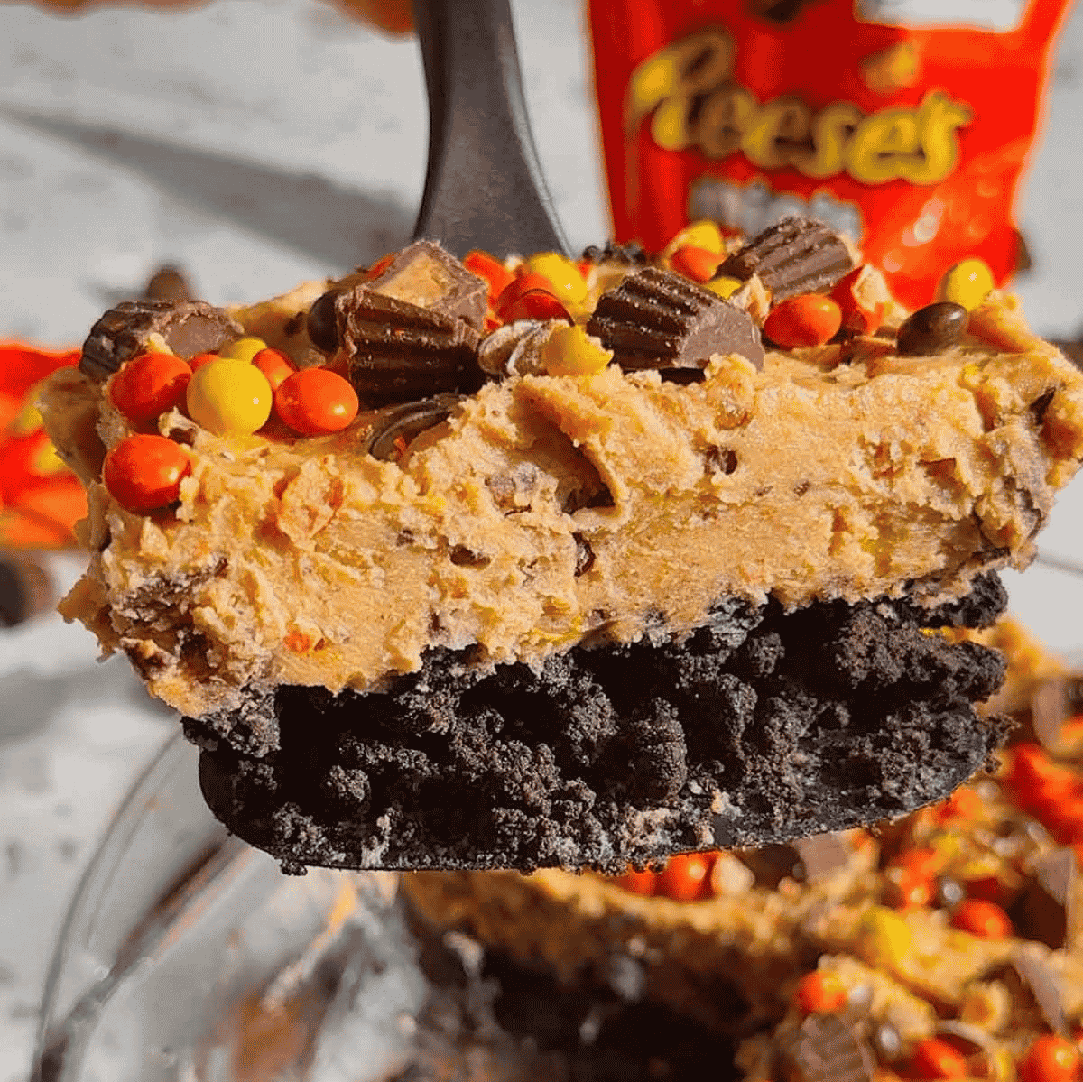 This No Bake Loaded Reese’s Cheesecake is the ultimate peanut butter chocolate dessert for Reese’s lovers! Made with an Oreo cookie crust, creamy peanut butter cheesecake filling, Cool Whip, mini Reese’s peanut butter cups, and Reese’s Pieces, this easy no bake cheesecake is perfect for parties, potlucks, holidays, birthdays, and family gatherings. This 9 x 13 dessert recipe is rich, sweet, creamy, crunchy, and loaded with candy in every bite. If you need easy no bake desserts, peanut butter cheesecake recipes, Oreo crust desserts, Reese’s desserts, or make ahead desserts for a crowd, this loaded Reese’s cheesecake is a must try treat!