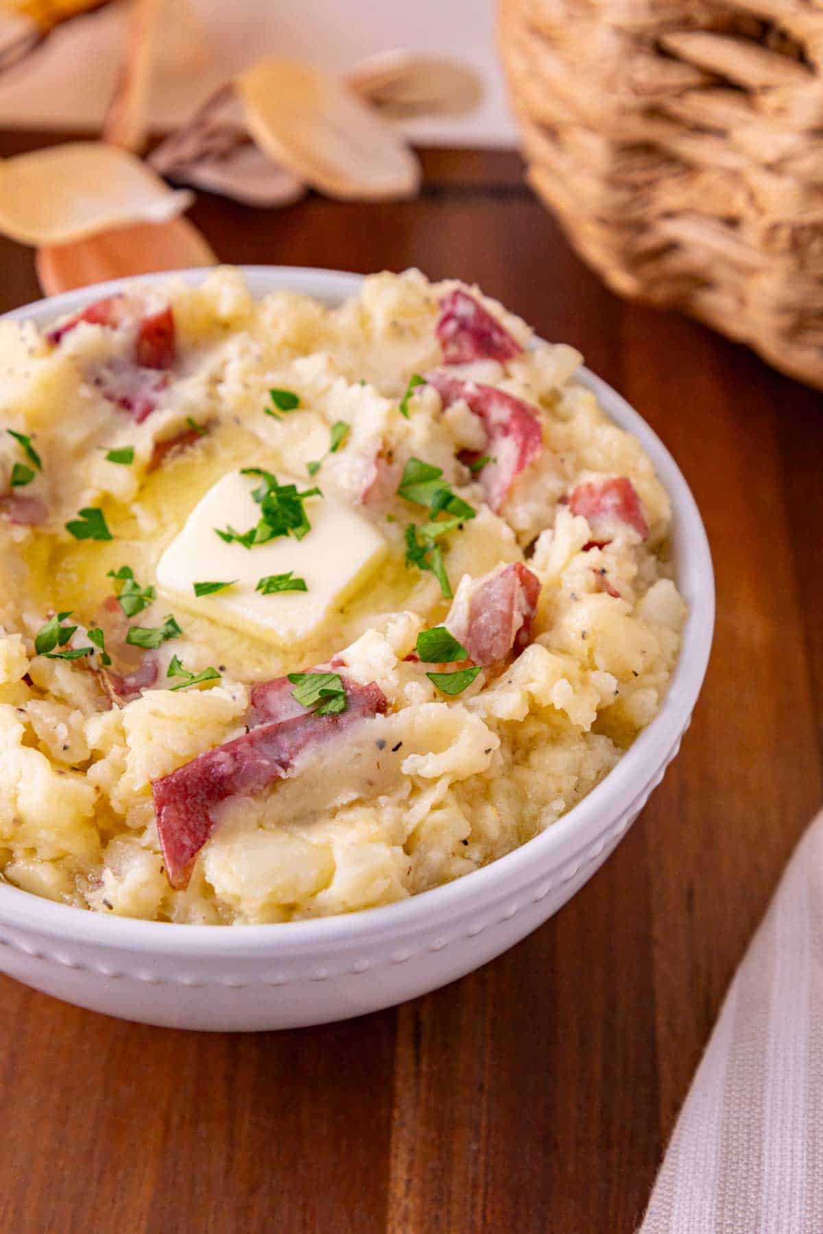 butter and parsley on top of garlic mashed potatoes in a serving bowl
