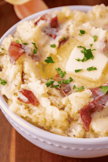 Red Skin Garlic Mashed Potatoes are an easy potato side dish made with red potatoes, butter, fresh garlic, milk, and Parmesan cheese. These creamy garlic mashed potatoes have tender potato skins in every bite, so you can skip the peeling and get this family favourite on the table in just 30 minutes. Serve these buttery Parmesan mashed potatoes with meatloaf, roast chicken, steak, or pork chops for an easy weeknight dinner. This red skin mashed potatoes recipe is also perfect for Thanksgiving dinner, Christmas dinner, Sunday supper, and holiday meals. Mash them smooth or leave them chunky, then finish with extra butter and fresh herbs. Save this homemade mashed potatoes recipe for a simple, comforting side dish everyone will want seconds of!