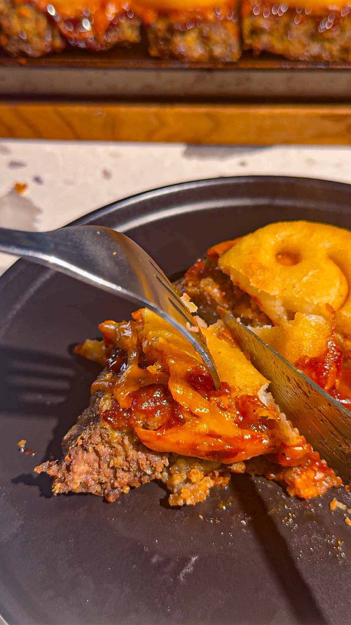 cutting a bite off of sheet pan meatloaf