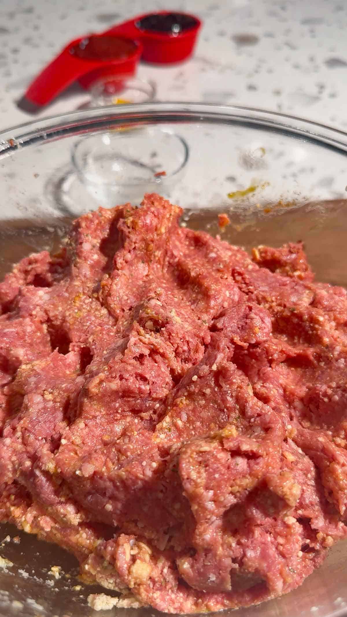 raw meatloaf mixture in a glass mixing bowl