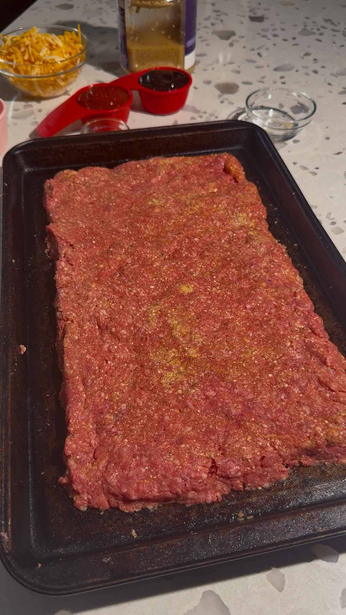 raw meatloaf mixture spread on a sheet pan