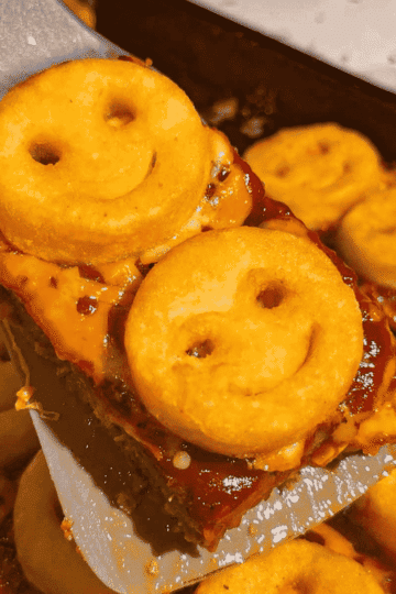 This Sheet Pan Meatloaf with Smiley Potatoes is an easy family dinner recipe loaded with seasoned ground beef, cheddar cheese, tangy ketchup BBQ sauce and crispy frozen smiley fries baked right on top. This kid friendly meatloaf recipe is perfect for busy weeknights, picky eaters, school night dinners and fun comfort food meals the whole family will love. Made with lean ground beef, bread crumbs, eggs, garlic, onions, shredded cheese and Sweet Baby Ray’s BBQ sauce, this sheet pan dinner is hearty, cheesy and simple to prep. Save this easy ground beef recipe for quick weeknight dinners, family meal ideas, meatloaf recipes, kid approved dinners, freezer potato recipes and fun dinner ideas for kids.