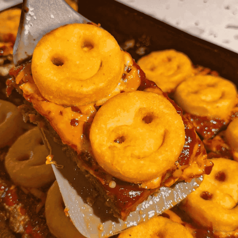 This Sheet Pan Meatloaf with Smiley Potatoes is an easy family dinner recipe loaded with seasoned ground beef, cheddar cheese, tangy ketchup BBQ sauce and crispy frozen smiley fries baked right on top. This kid friendly meatloaf recipe is perfect for busy weeknights, picky eaters, school night dinners and fun comfort food meals the whole family will love. Made with lean ground beef, bread crumbs, eggs, garlic, onions, shredded cheese and Sweet Baby Ray’s BBQ sauce, this sheet pan dinner is hearty, cheesy and simple to prep. Save this easy ground beef recipe for quick weeknight dinners, family meal ideas, meatloaf recipes, kid approved dinners, freezer potato recipes and fun dinner ideas for kids.
