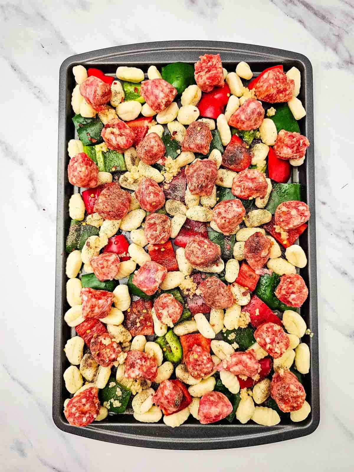 sausage and gnocchi on a baking sheet before cooking