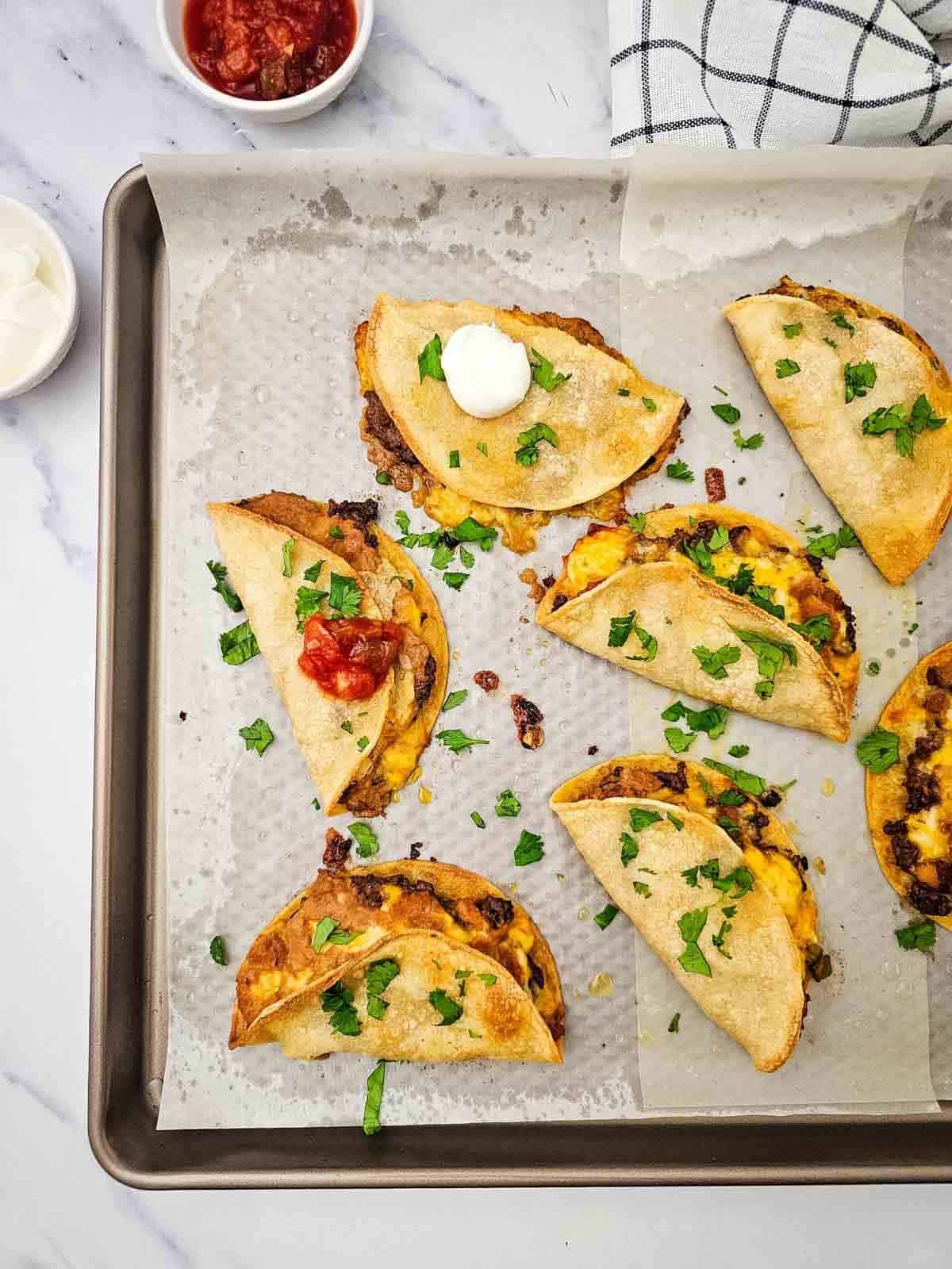 cilantro, sour cream and salsa on top of sheet pan tacos