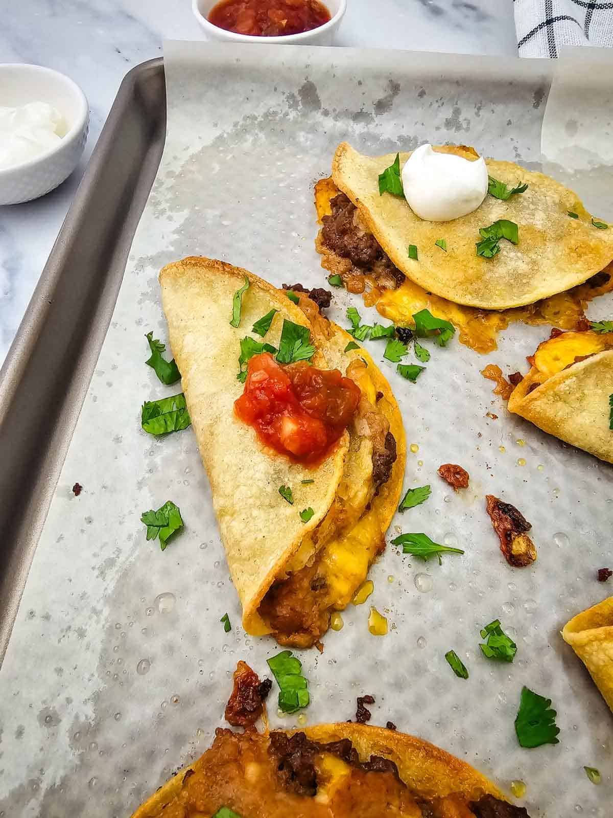 salsa and sour cream on top of sheet pan tacos