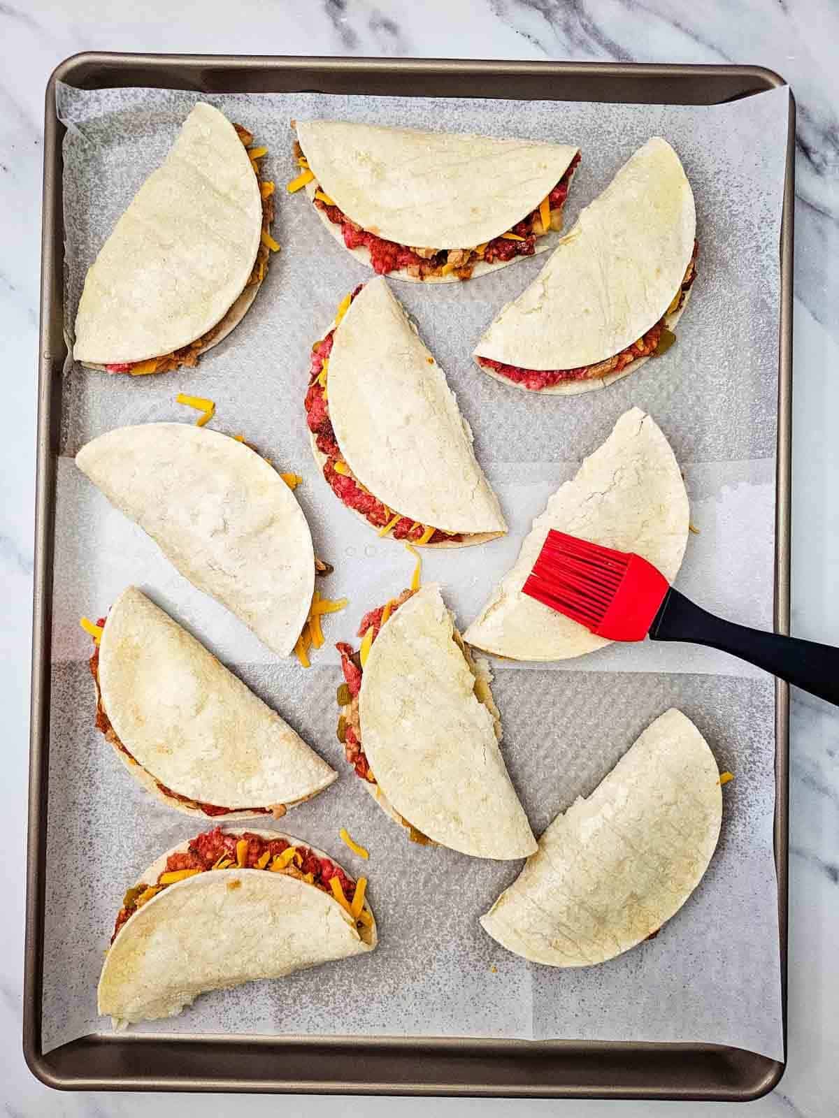 olive oil being brushed on sheet pan tacos
