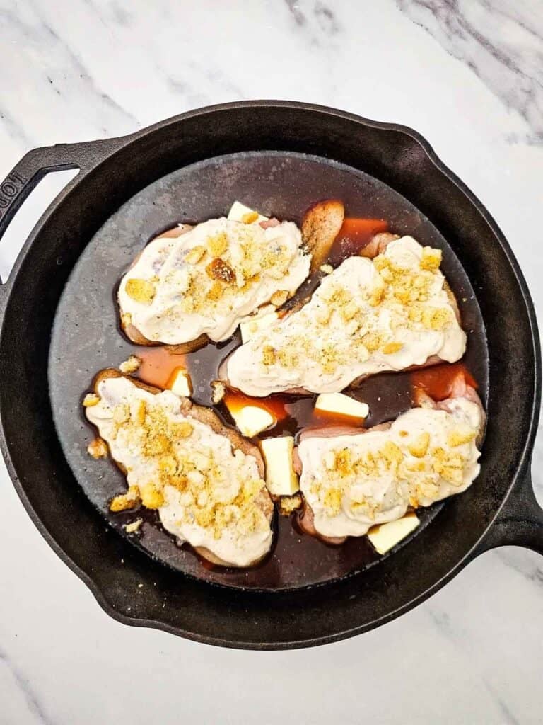 crushed croutons and provolone cheese on top of chicken breast in a skillet