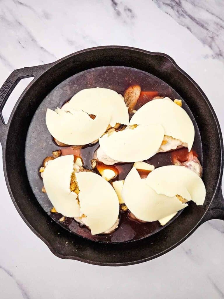 provolone slices on top of chicken breasts in a skillet