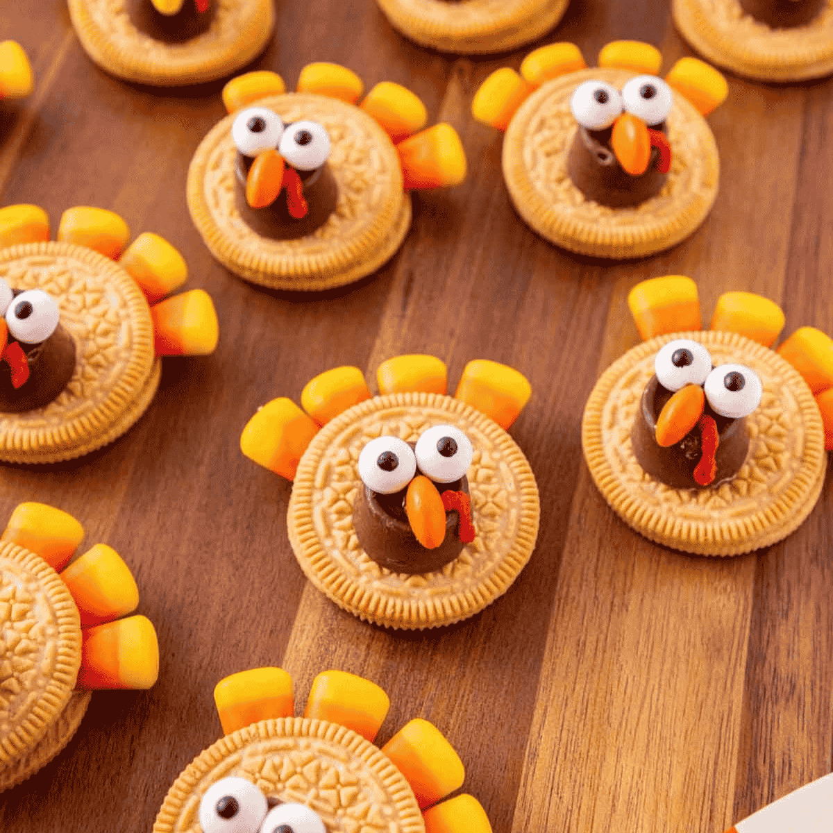 These Golden Oreo Turkey Cookies are the cutest no bake Thanksgiving treat for kids and adults. Made with Golden Oreos, Rolos, candy corn, candy eyeballs, Reese's Pieces and red decorating icing, these easy turkey cookies are perfect for Thanksgiving dessert tables, classroom parties, holiday baking trays and fun fall food ideas. This simple Oreo turkey cookie recipe comes together in about 20 minutes with melted chocolate candy melts holding everything in place. If you need Thanksgiving cookies, cute turkey desserts, no bake fall treats, Golden Oreo desserts, Thanksgiving party food, edible turkey crafts or easy holiday recipes kids can help decorate, these adorable Golden Oreo and Rolo turkeys are a festive little win for your holiday spread.