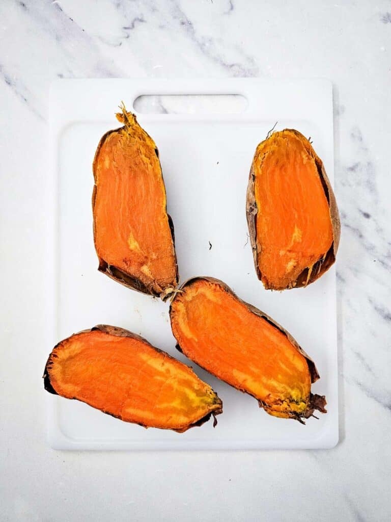 cooked sweet potatoes cut in half on a cutting board
