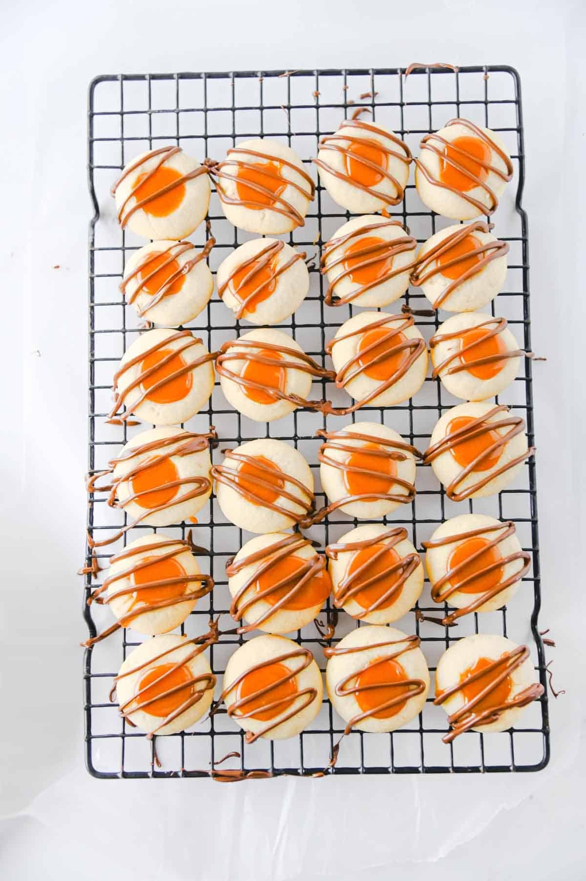 chocolate drizzled over twix cookies on a cooling rack