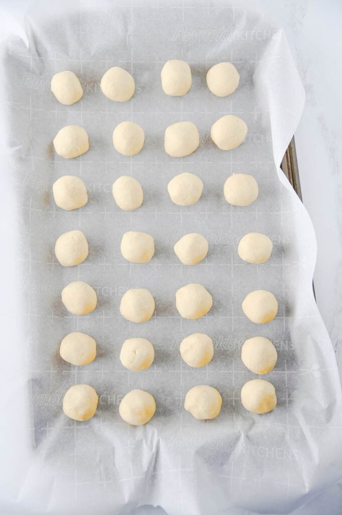 twix cookie dough balls on a parchment lined baking sheet
