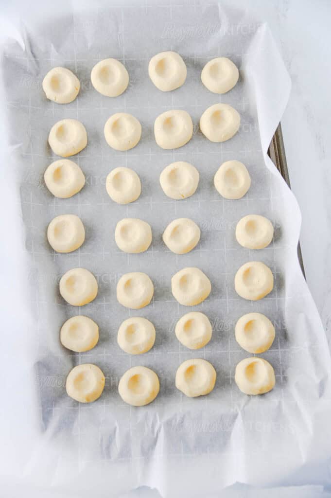 thumbprint cookies on a parchment lined baking sheet