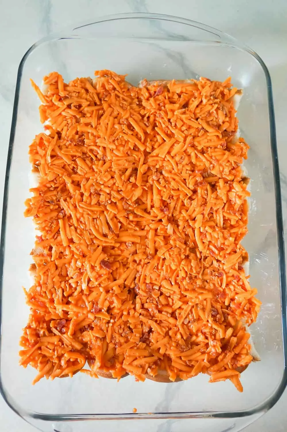 shredded cheddar cheese and bacon mixture in a baking dish