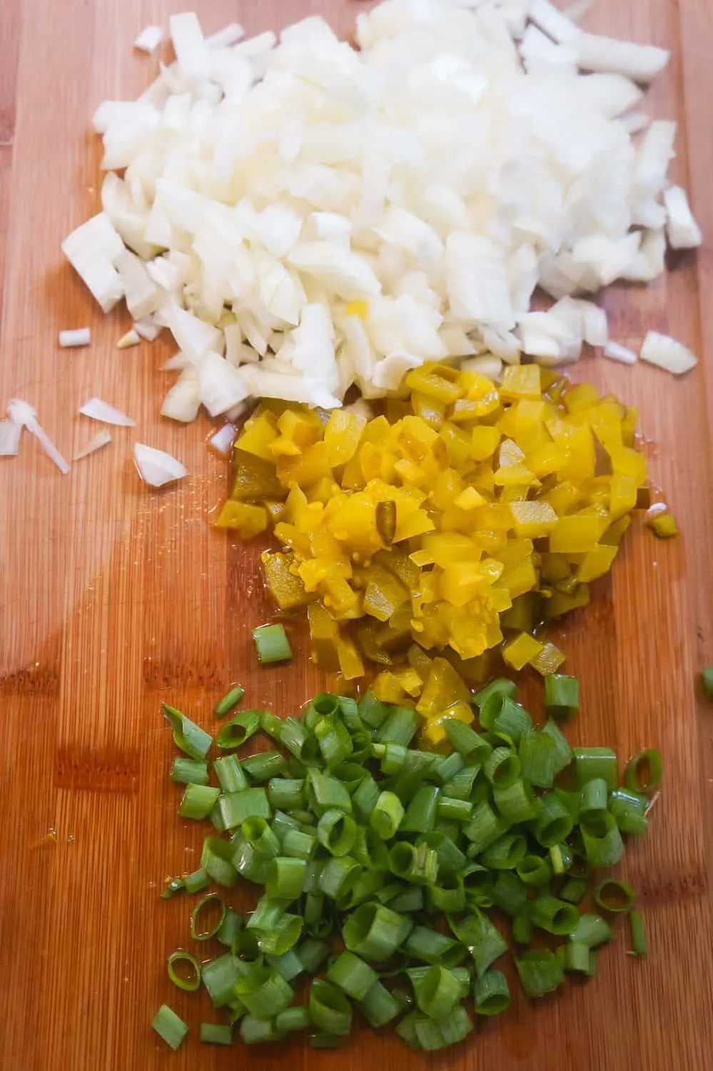 diced onion, diced pickles and chopped green onions on a cutting board