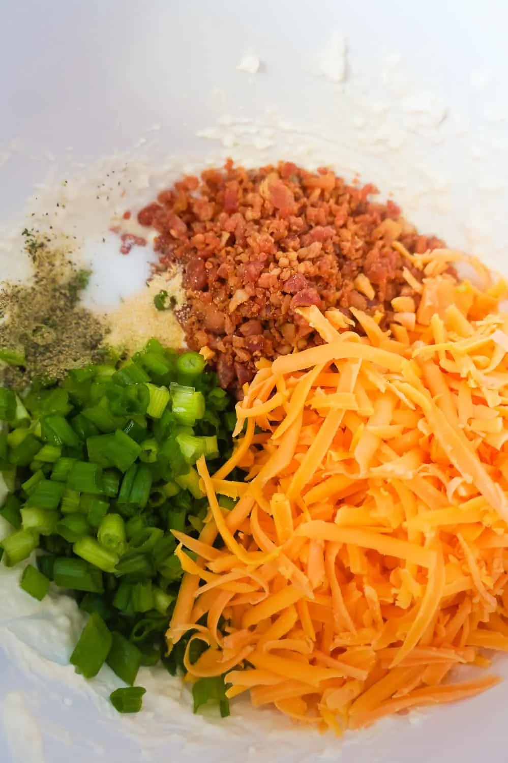 shredded cheddar cheese, real bacon bits and chopped green onions in a mixing bowl