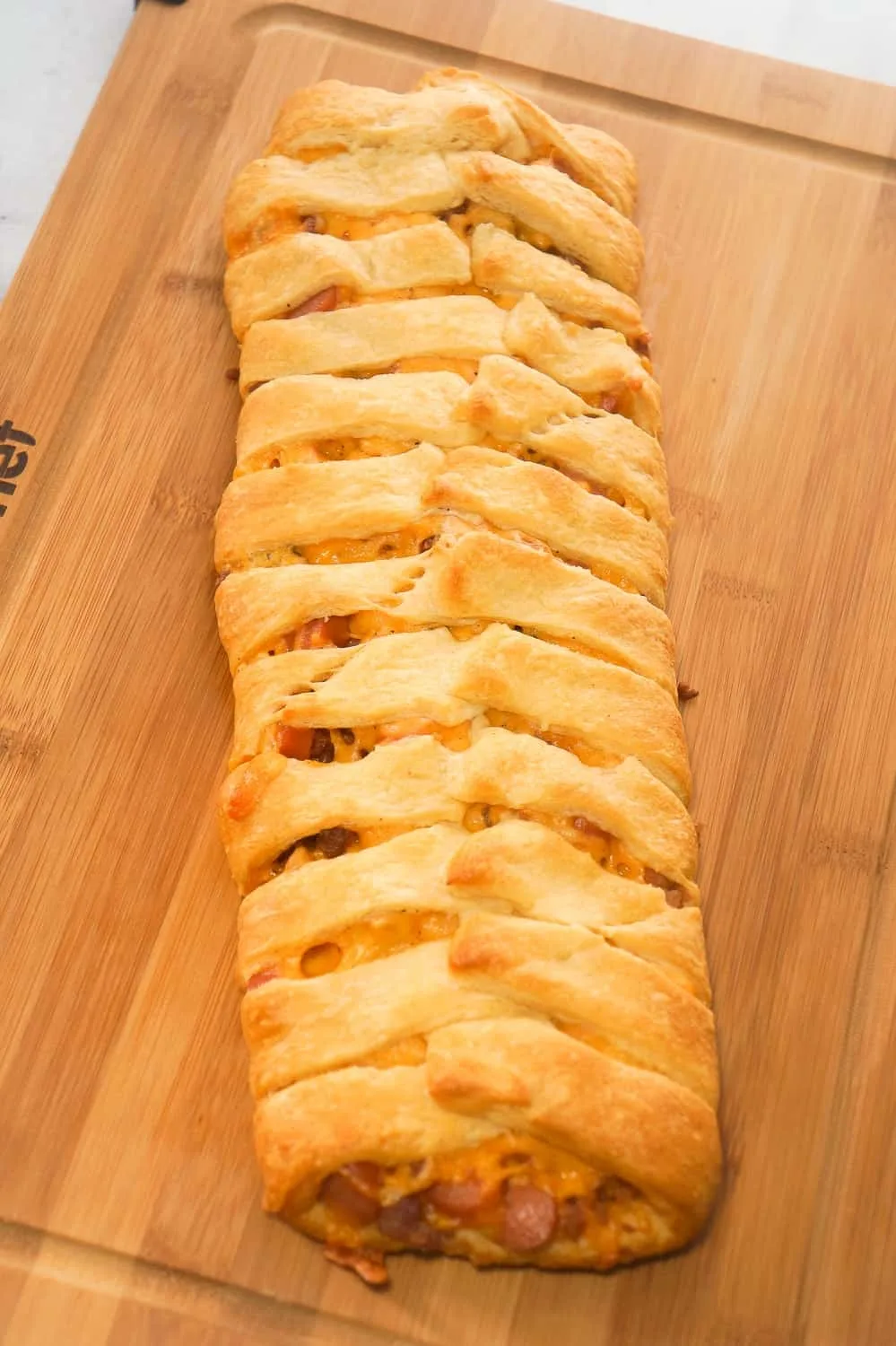 Bacon Cheese Dog Crescent Braid is an easy weeknight dinner recipe. This crescent bake is stuffed with wieners, bacon and cheese then topped with chili to make it a hearty comfort food dish.