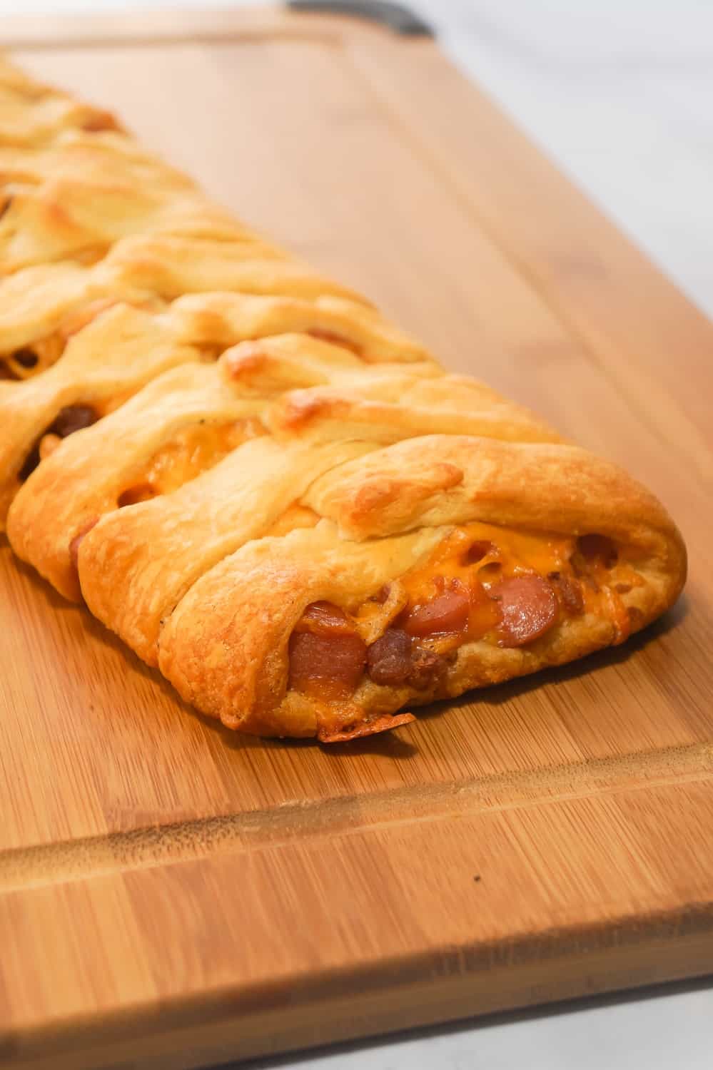 Bacon Cheese Dog Crescent Braid is an easy weeknight dinner recipe. This crescent bake is stuffed with wieners, bacon and cheese then topped with chili to make it a hearty comfort food dish.