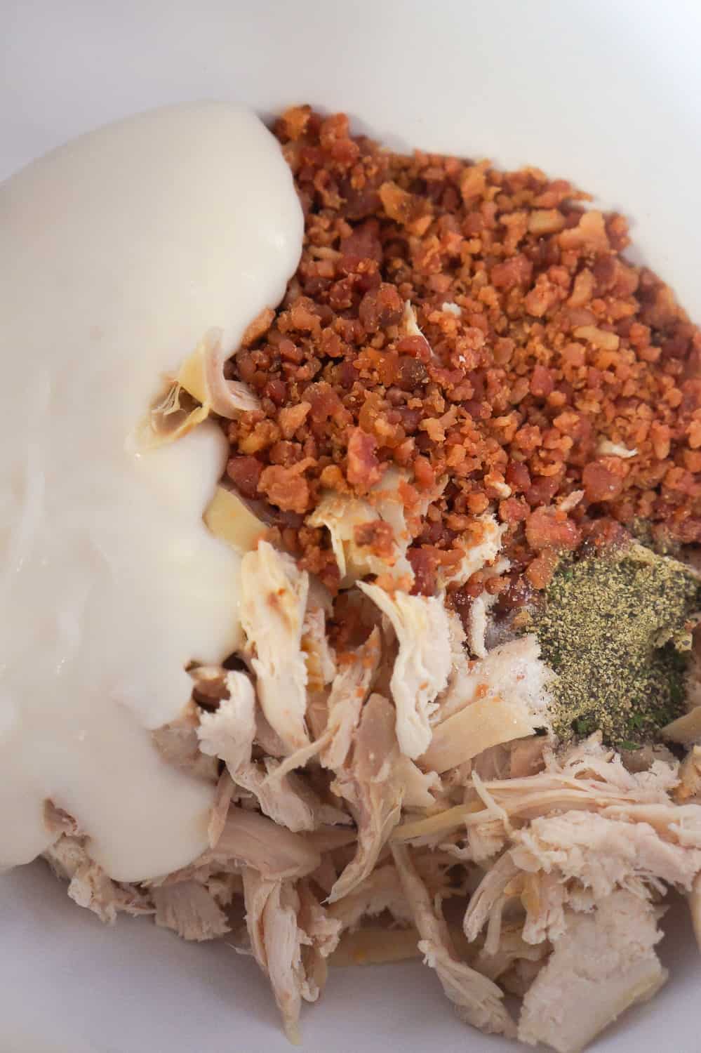 shredded chicken, bacon bits and Alfredo sauce in a mixing bowl