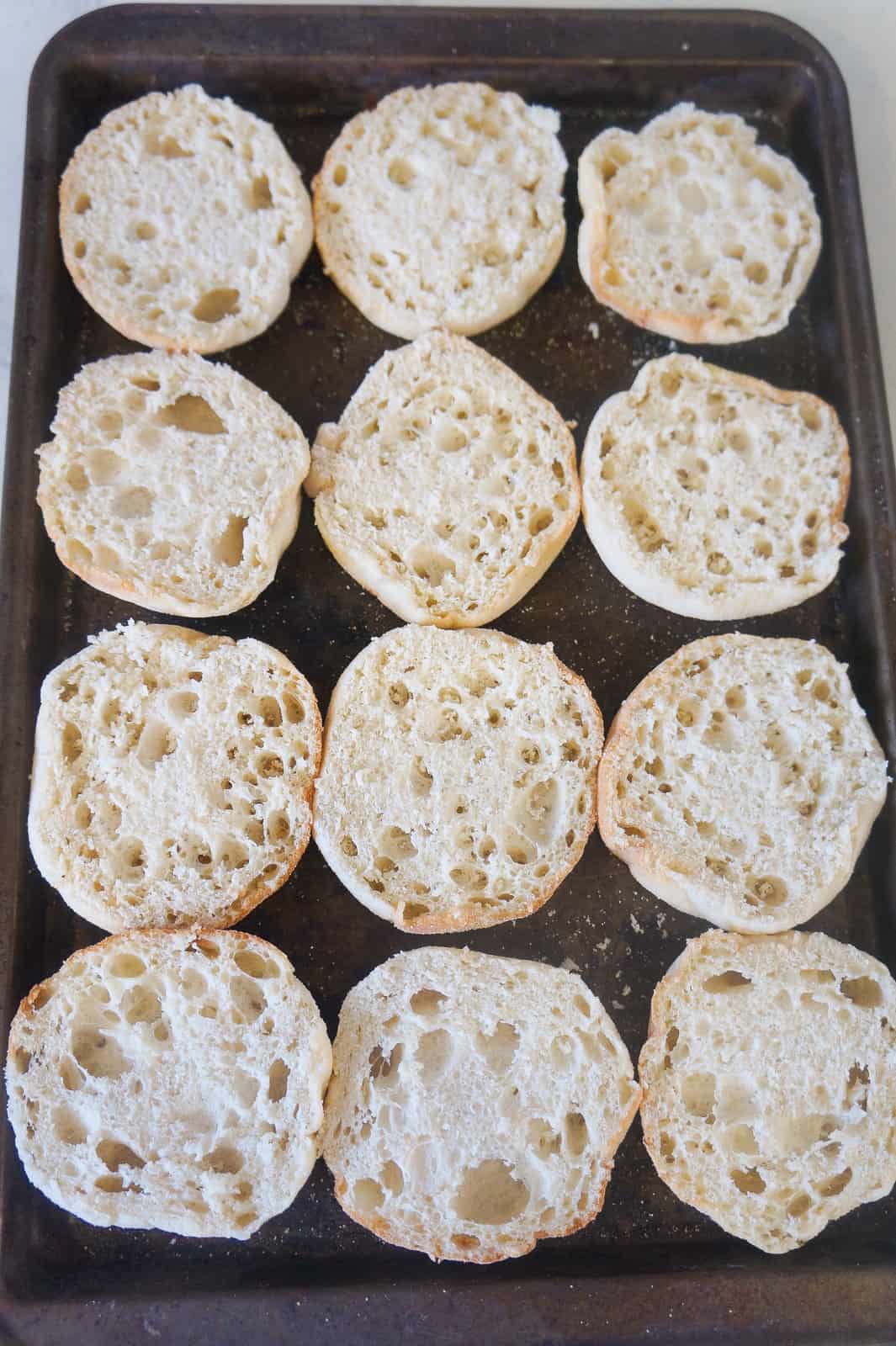 sliced English muffins on baking sheet