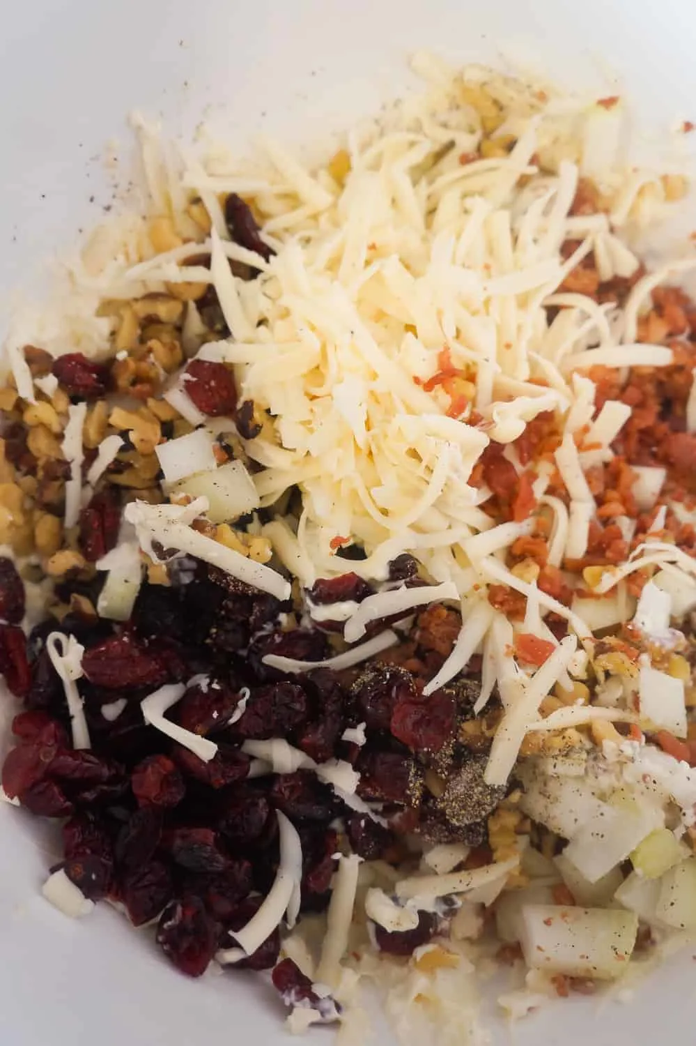 dried cranberries, shredded Swiss cheese, bacon bits and chopped walnuts in a mixing bowl