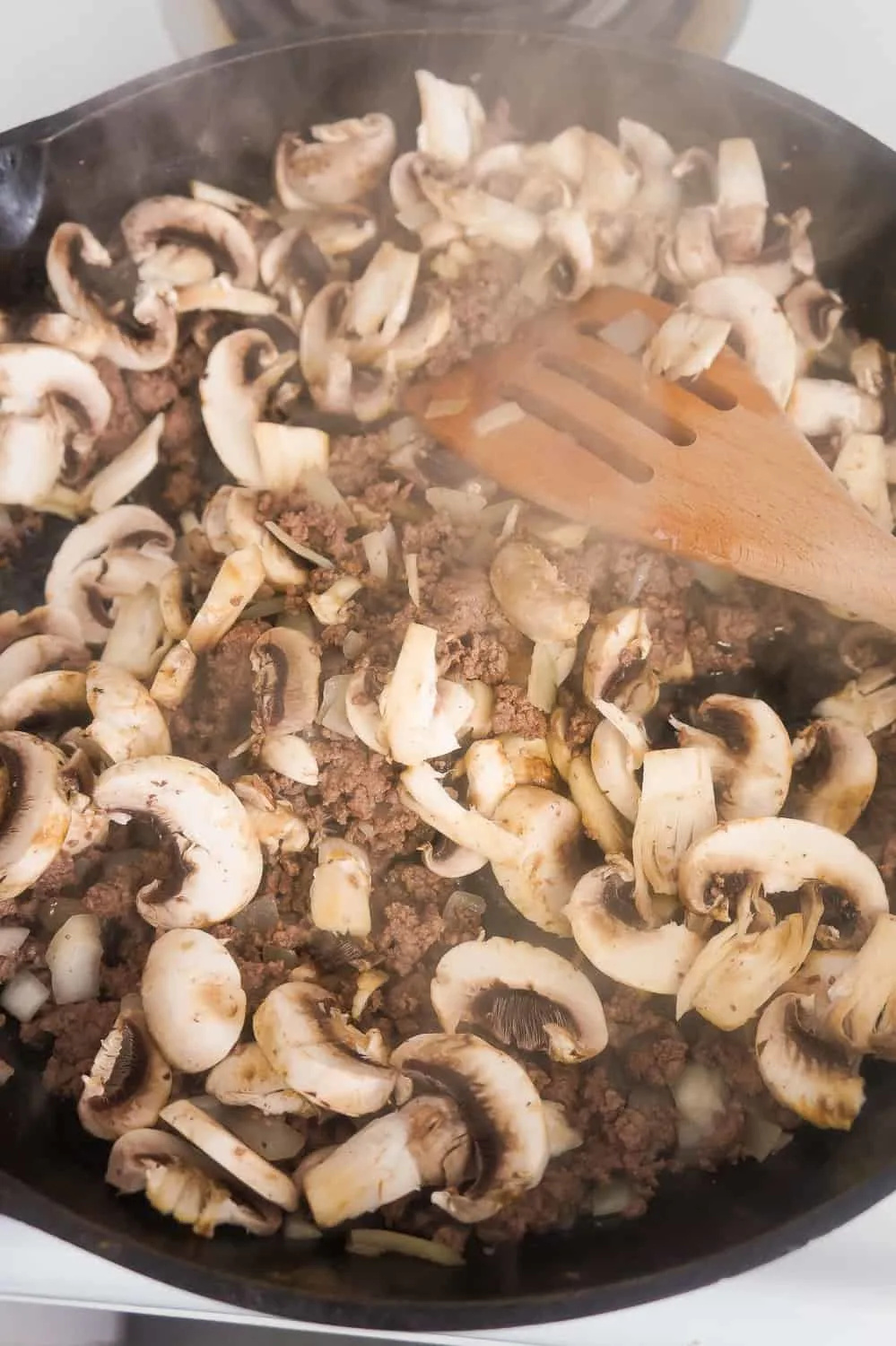 sliced mushrooms in skillet with ground beef