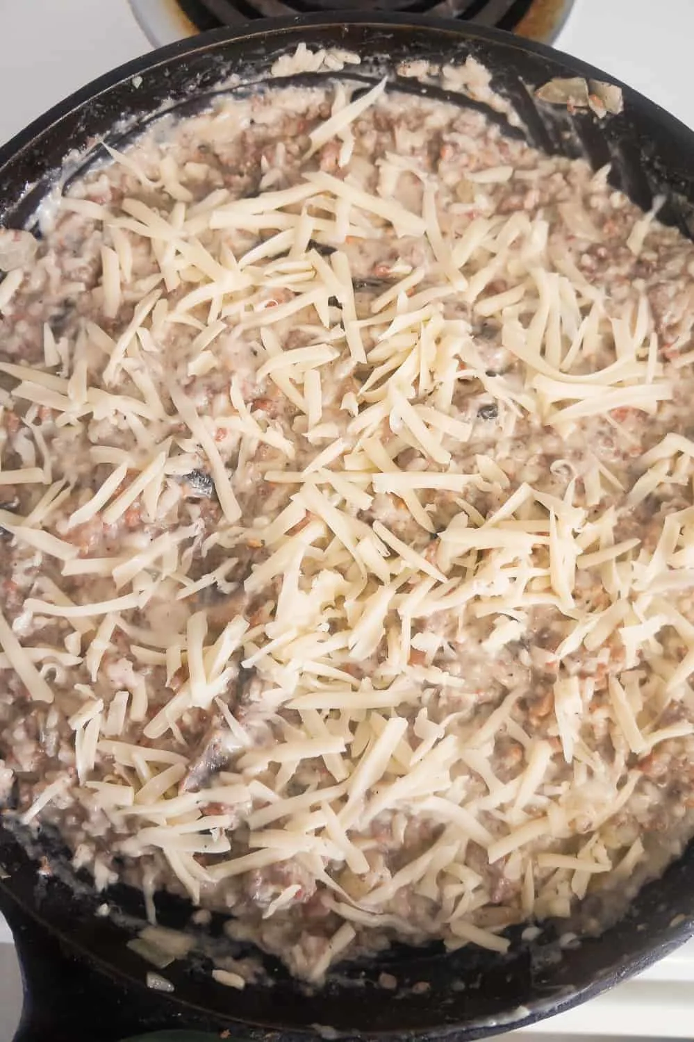 shredded Swiss cheese on top of ground beef and rice