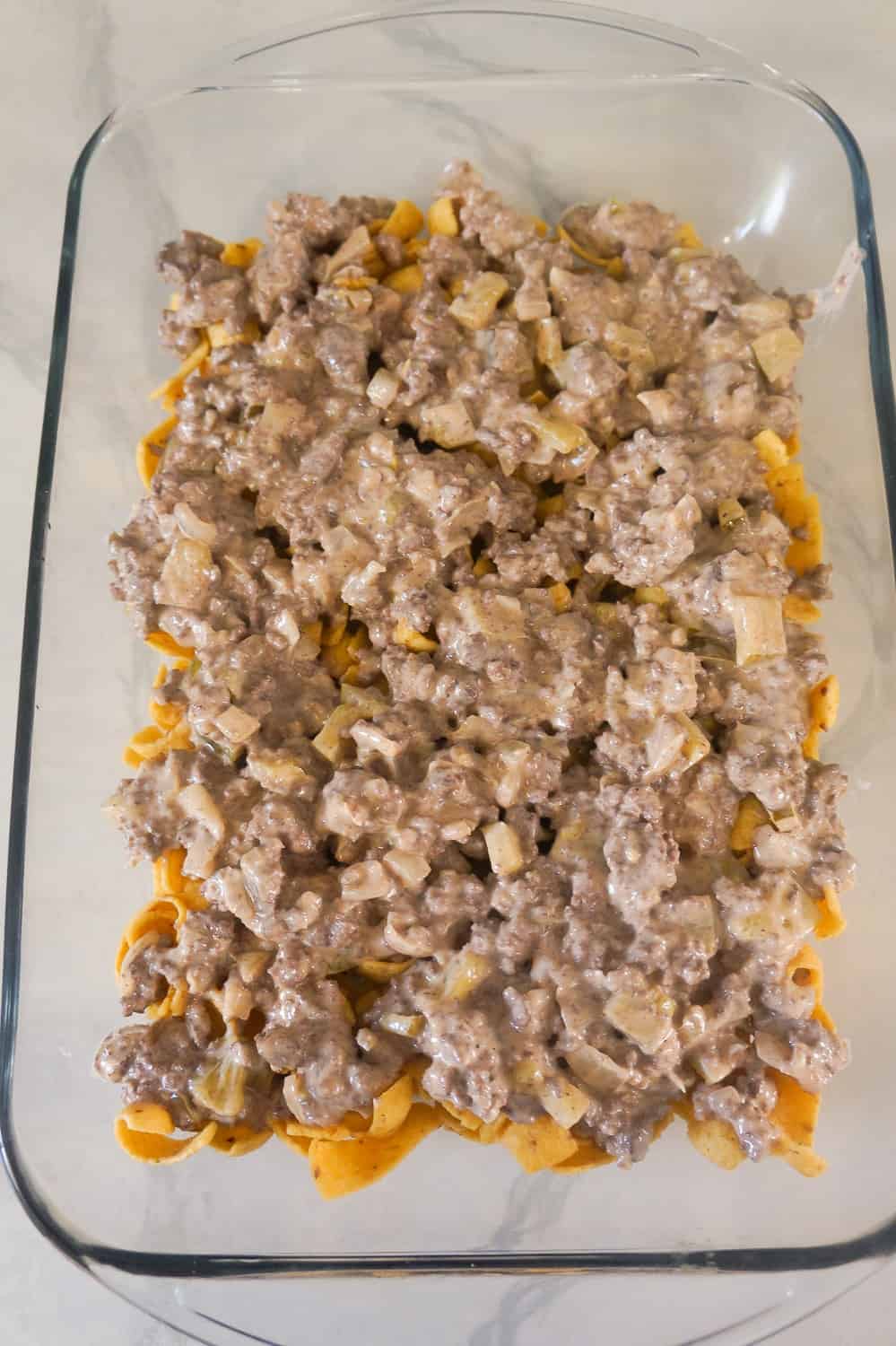 ground beef mixture on top of corn chips in baking dish