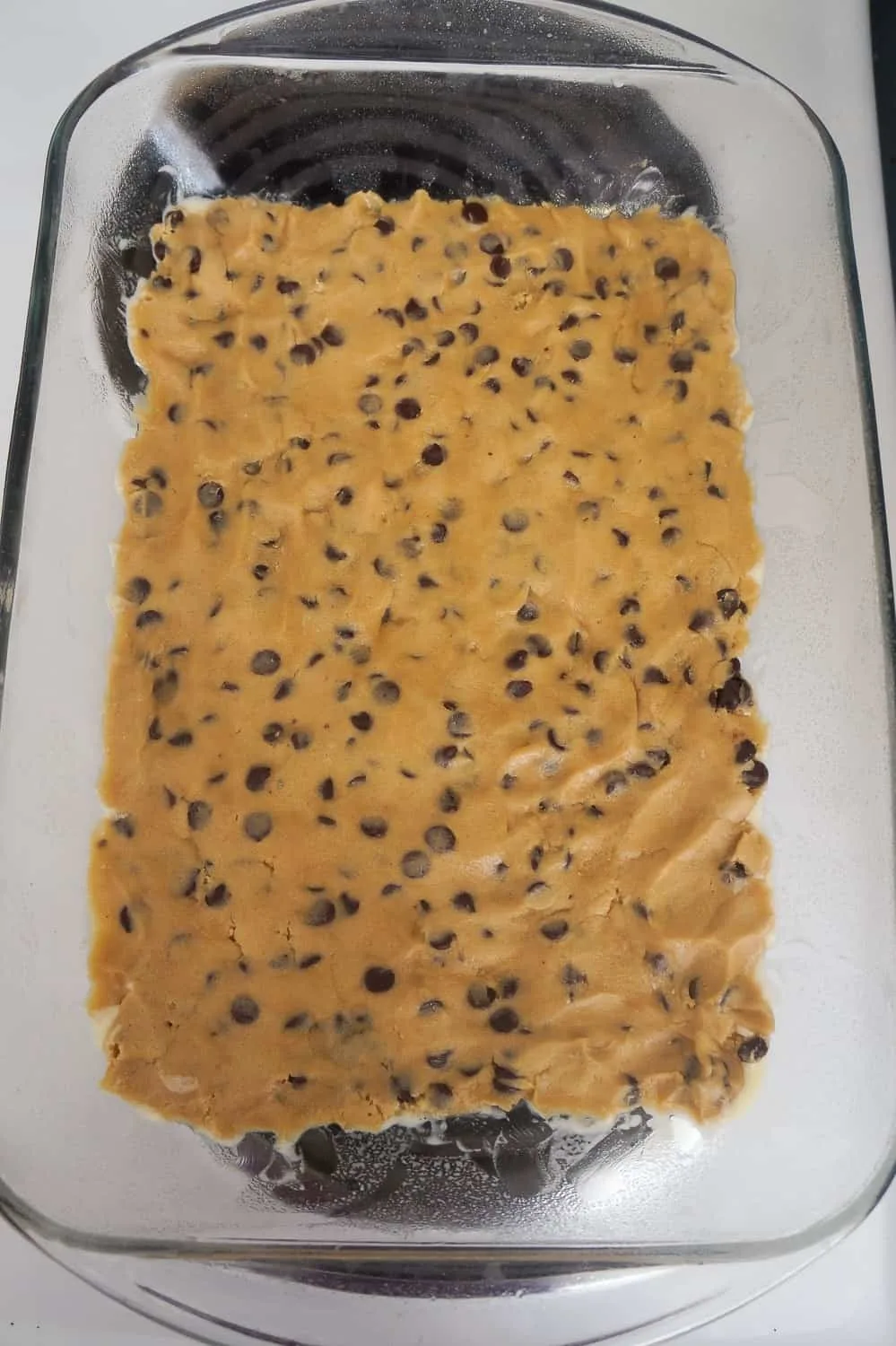 raw cookie dough pressed into the bottom of a baking dish