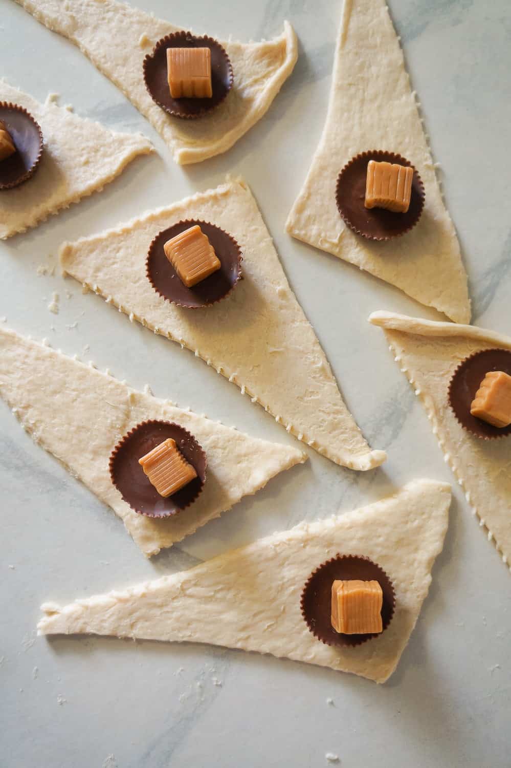 caramels and peanut butter cups on top of triangles of crescent roll dough