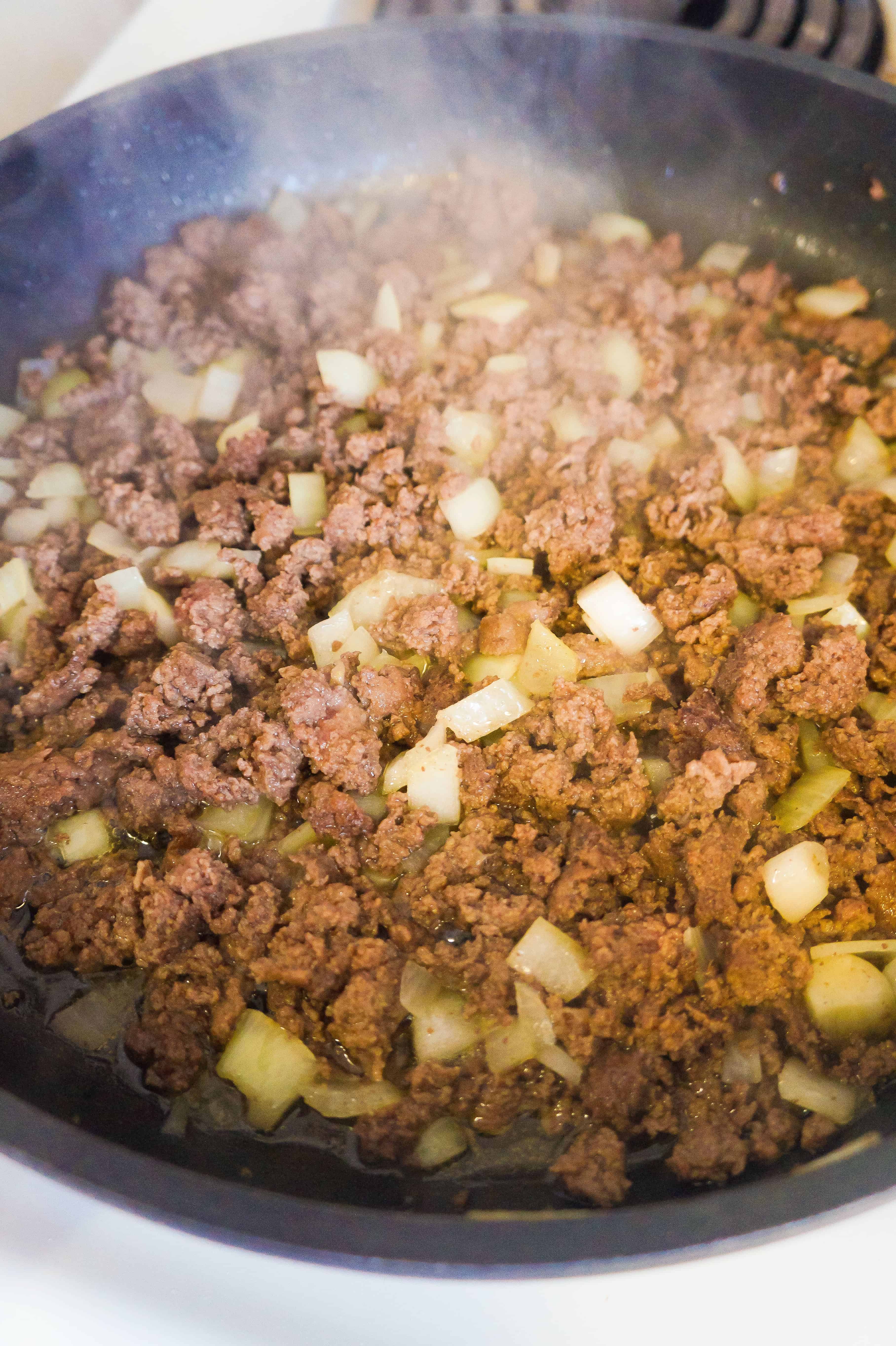 Ground beef and diced onions in frying pan.